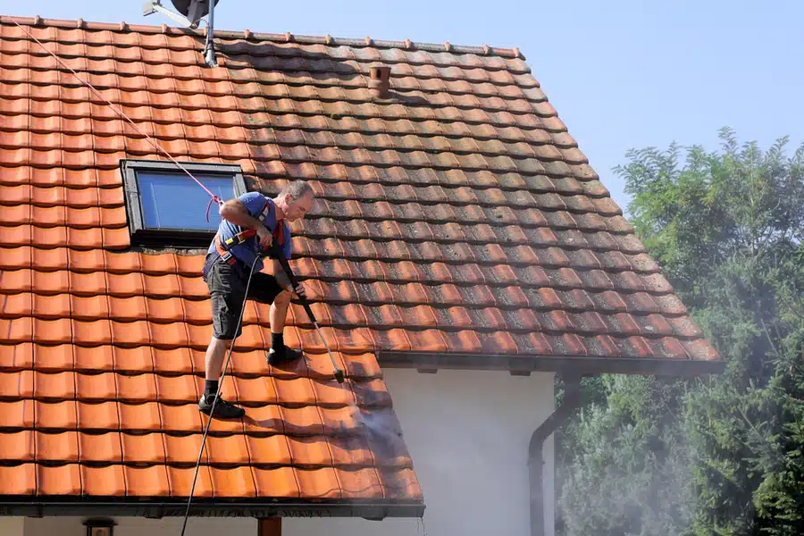 En mann som vasker et tak med høytrykkspyler